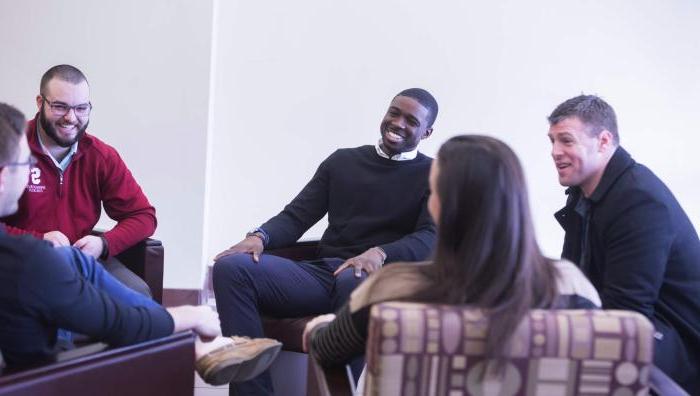 Graduate Students sit in chairs laughing